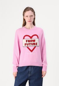 Il maglione lavorato a maglia rosa presenta un design a cuore con la scritta "DAL FUTURO" su un banner crema. I polsi e l'orlo a coste completano il taglio rilassato.