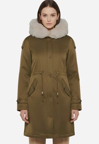Giacca parka imbottita verde oliva con colletto in pelliccia sintetica grigia chiara rimovibile, chiusure con zip e bottoni a pressione, e vita con coulisse e tasche frontali.