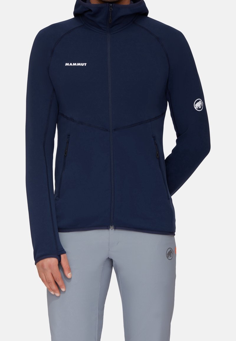 Marineblaue Mammut-Jacke mit durchgehendem Reißverschluss, figurbetontem Schnitt, elastischen Bündchen, Reißverschlusstaschen und Logodetail auf Brust und Ärmel.