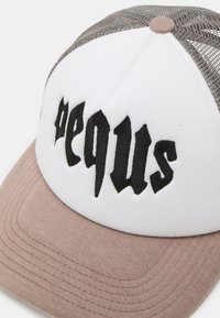 Vit och beige keps med rund skärm, med svart broderad text. Nätbeklädnaden ger andningsförmåga; mjuk textur över hela kepsen.