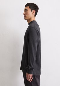 Długi rękaw, ciemnoszary sweter z wysokim kołnierzem i gładką fakturą. Charakteryzuje się luźnym krojem i subtelnymi detalami na bocznym obszyciu.