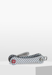 Multiverktyg i kolfiber och silvermetall. Har ett rött schweiziskt kors-emblem, ihopvikbar design och slät yta.
