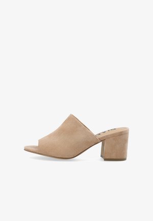 Mules en daim beige à bout ouvert avec un talon bloc, présentant une texture lisse et un design ample sur le dessus. Pas de matériel visible ni de motifs.