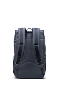 Tamnosivi ruksak s jastučićem na leđima, dvostrukim podesivim trakama i bočnom džepom. Ima zippered odjeljak na vrhu. Teksturirani materijal.