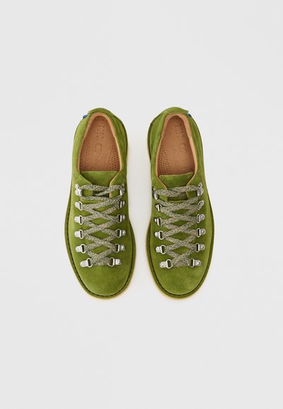 Vihreät mokkanahkakengät, joissa on matala profiili, sileä pinta, metalliset nauhalenkit ja harmaat punotut nauhat. Sisävuori on vaaleanruskeaa nahkaa.