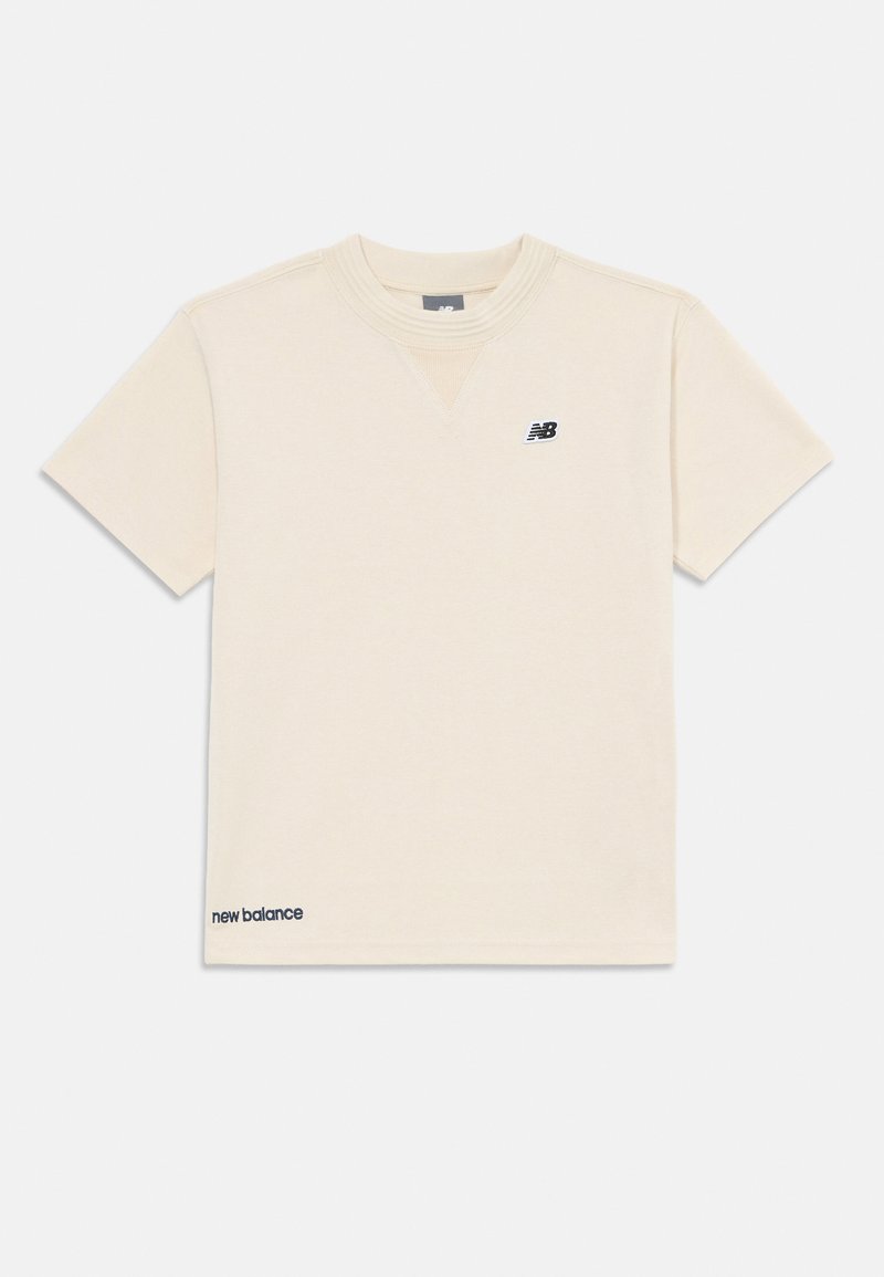 Camiseta de manga corta color crema hecha de tejido suave, con un escote en forma de V, un pequeño logo negro en el pecho y "new balance" bordado en color marino en el dobladillo.