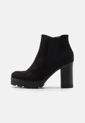Sort ruskind ankle støvle med kraftig blokhæl, elastisk sidepanel og grov sål for ekstra greb.