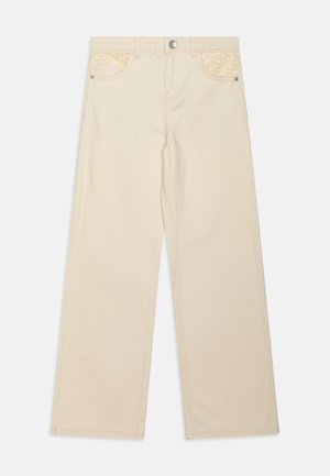 Beige vide bukser laget av denim, med teksturerte lommer med blomstermønster og en frontknapplukking med sølvfarget hardware.