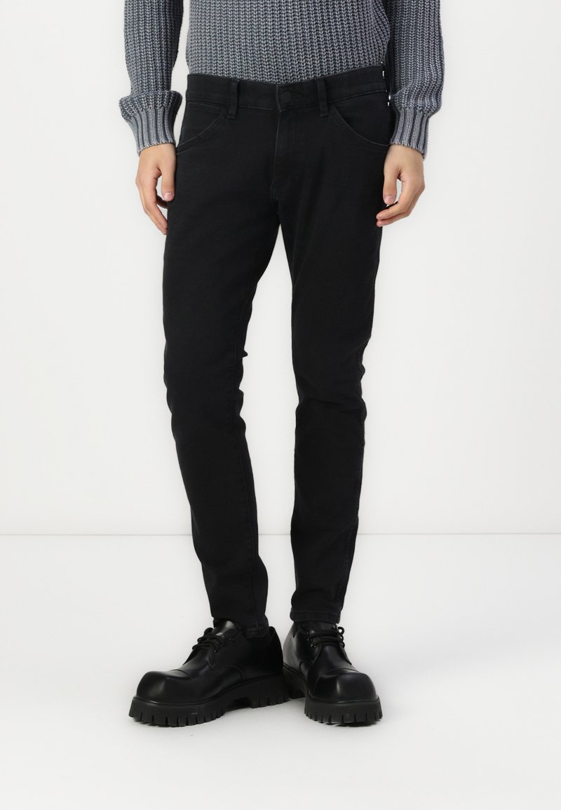 Mustad teksad sileda tekstuuriga, viie tasku disainiga ja nähtava õmblusega. Koos mahuka musta nööbitava saapaga.