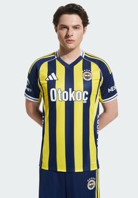 Geltonas ir tamsiai mėlynas dryžuotas futbolo marškinėliai su V formos iškirpte, su logotipu ir prekės ženklu ant krūtinės bei rankovių. Pabaigtas su tamsiai mėlynomis šortais.