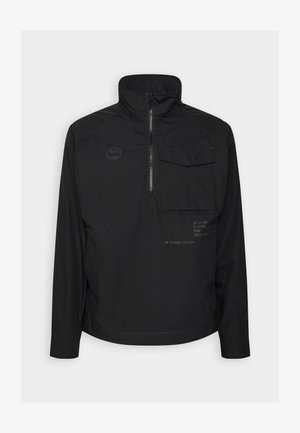 Melnā puloverjakā ar pus-izsiti, augstu apkakli, priekšējo kabatu un drukātu tekstu. Izgatavots no gludas, vieglas auduma.