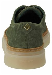 Chaussure en daim vert avec une finition texturée, dotée d'une semelle extérieure beige, d'un design à lacets et d'un accent logo doré sur le talon.