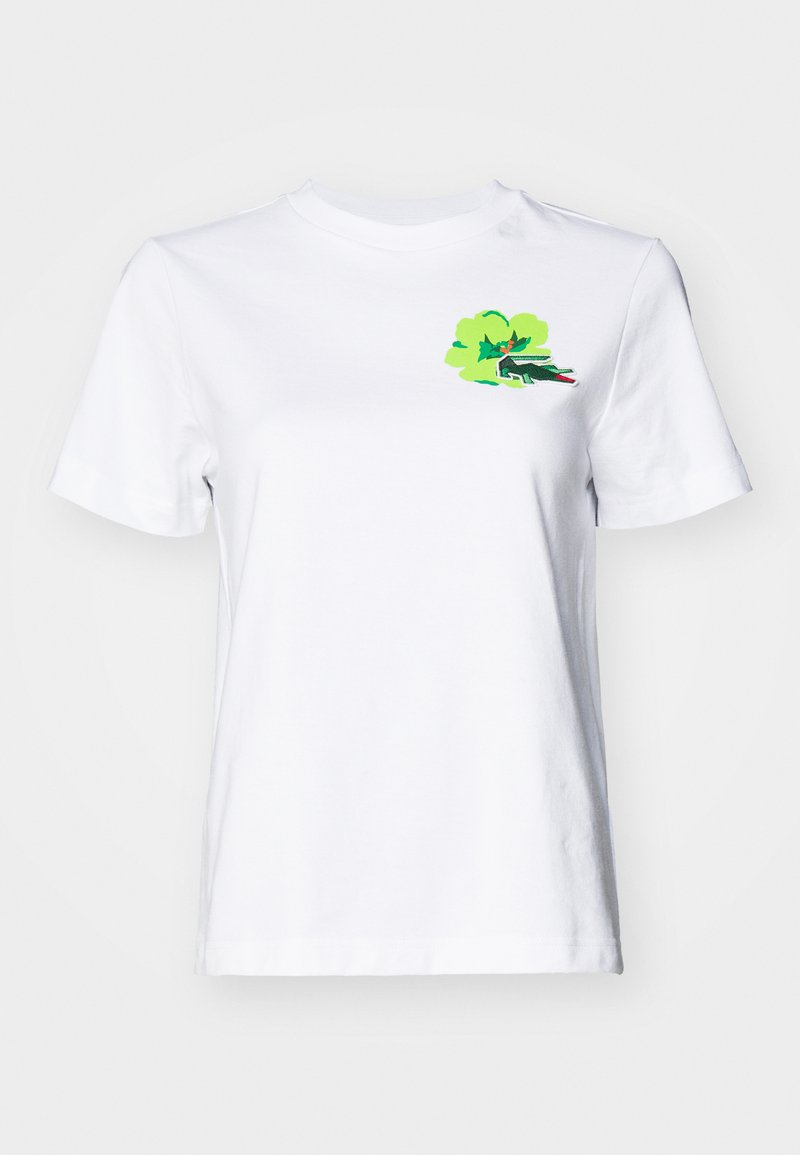 T-shirt in cotone bianco con collo rotondo e maniche corte. Presenta una grafica colorata di un dinosauro verde su uno sfondo verde chiaro.