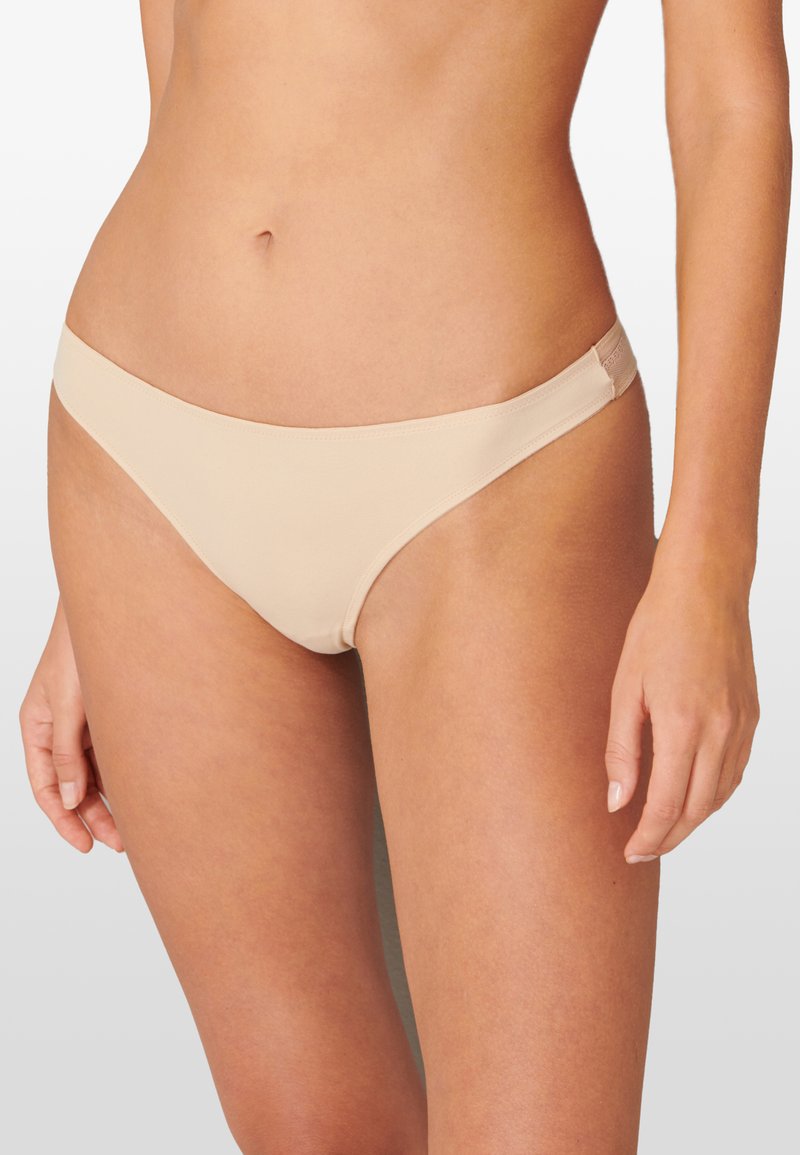 Bikini w kolorze cielistym z gładką fakturą, minimalistycznym designem i cienkim paskiem w talii. Zawiera subtelne przeszycia i brak dodatkowych akcentów.