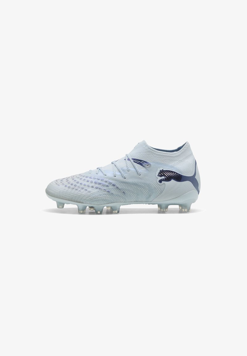 Chaussure de football blanche avec col mi-haut, dessus texturé, logo Puma bleu et crampons moulés sur la semelle extérieure.