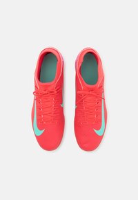 Scarpe rosse con superficie testurizzata, dotate di un logo Nike Swoosh azzurro, lacci e una fodera interna imbottita.