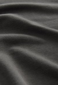 Tessuto grigio scuro con una morbida trama, caratterizzato da delicati motivi a onde e una superficie liscia. Ideale per abbigliamento o applicazioni di rivestimento.