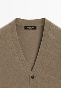 Brauner V-Ausschnitt-Cardigan aus strukturiertem Stoff, mit einem schwarzen Knopf auf der Vorderseite und mit "Massimo Dutti" im Kragenetikett.