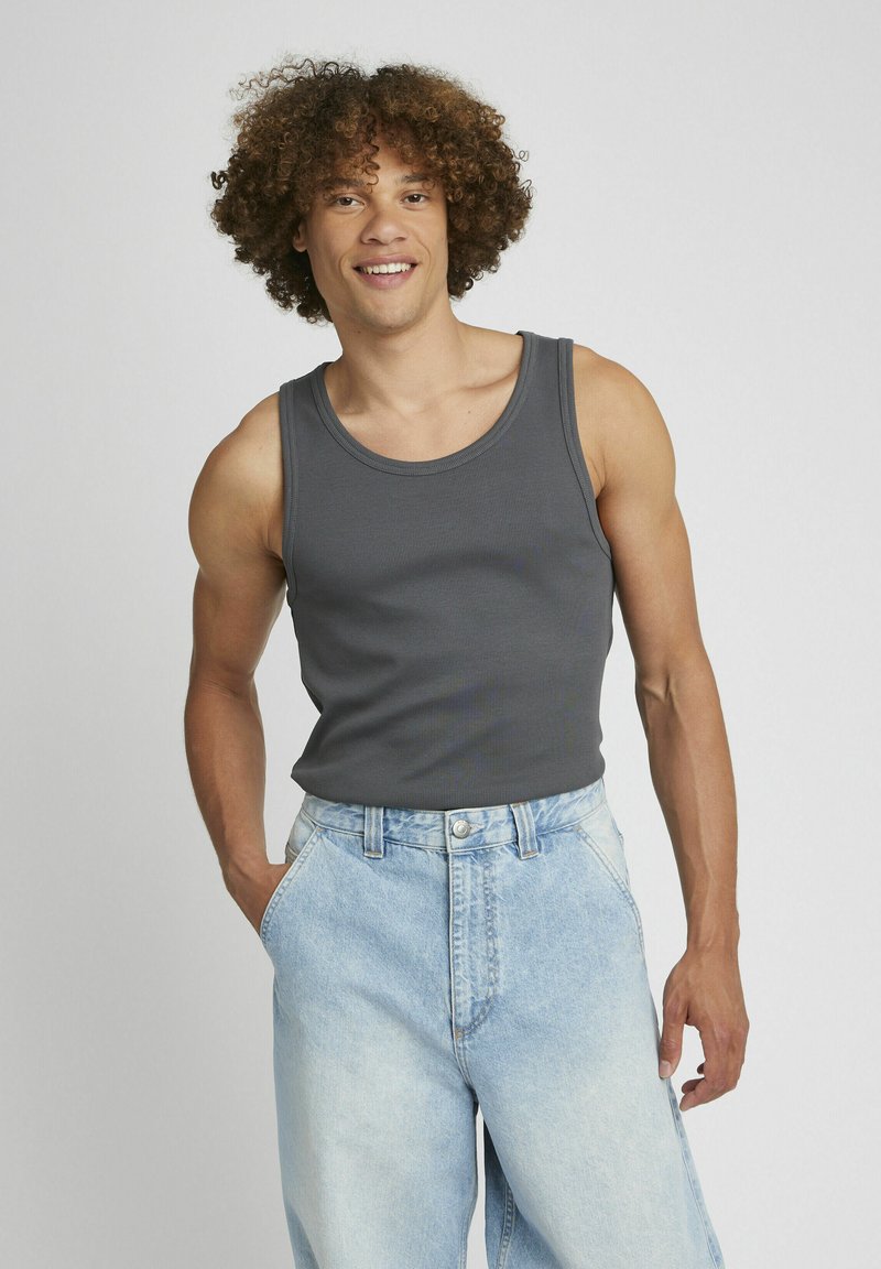 Débardeur gris à côtes avec des bretelles larges, associé à un short en denim bleu clair à coupe ample, doté d'une fermeture à bouton et de poches latérales.