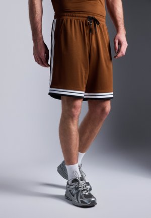 Bruna nätträningsshorts med svarta och vita accentfärger och sidostripes, utrustade med ett elastiskt midjeband och snörning, i kombination med grå löparskor.