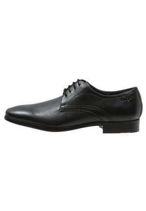 Chaussure habillée pour homme en cuir noir avec devant perforé, fermeture à lacets, petit talon et embossage discret de la marque sur le côté.