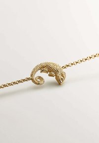 Pulsera de camaleón dorado con escamas texturizadas, una cola enroscada y eslabones de cadena. Presenta detalles intrincados en la cabeza y el cuerpo del camaleón.
