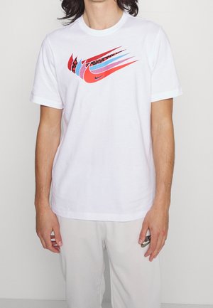 T-shirt en coton blanc avec un logo Nike coloré en rouge, bleu et noir. Col rond et manches courtes.