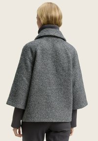 Getextureerde grijze wollen jas met een brede kraag en losse mouwen, met daaronder een ribbelkraag en een rechte snit aan de onderkant.