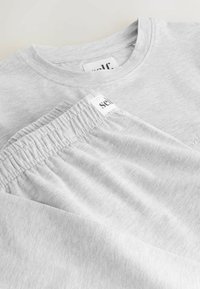 Szary zestaw z bawełnianą koszulką i spodniami o okrągłym dekolcie. Charakteryzuje się miękką fakturą i elastycznym pasem, z logo na każdej części.