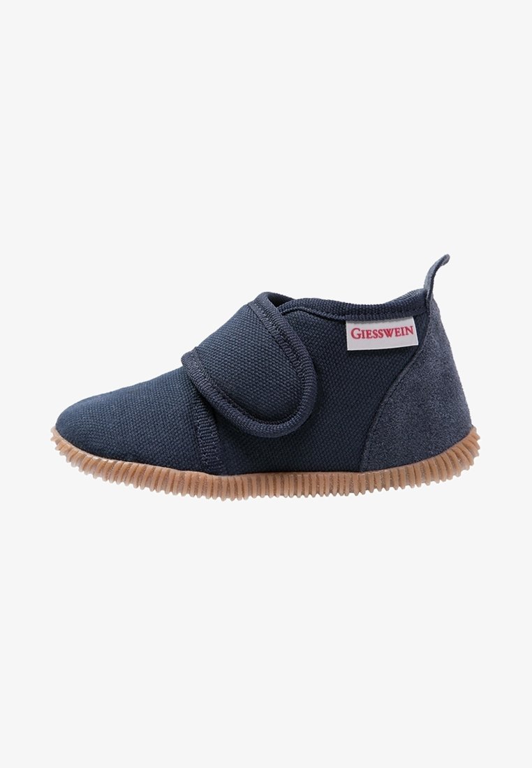 Chaussure bébé bleu marine en tissu texturé, sangle à fermeture auto-agrippante, semelle rainurée marron clair et étiquette de la marque Giesswein sur le côté.
