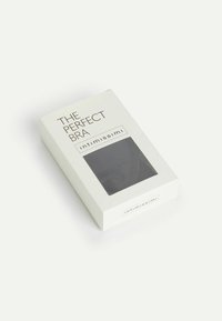 Czarny biustonosz zapakowany w białe pudełko z przezroczystym oknem. Napis na pudełku brzmi "IDEALNY BIUSTONOSZ" i "intimissimi". Prosty design.