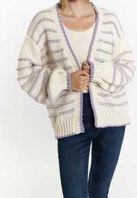 Cardigan en maille oversize crème avec des rayures lavande. Comprend un col en V, des bords côtelés et des manches amples. Texture douce et coupe décontractée.