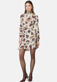 Blumenkleid mit weißem Grund, das burgunderfarbene und orangefarbene Blumen zeigt, mit langen Ärmeln, rüschigem Kragen und ausgestelltem Saum.