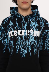 Black hoodie featuring a blue lightning pattern and bold white "ice cream" text across the chest. Soft fabric with a kangaroo pocket.