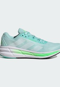 Zapatilla de correr de color verde azulado claro con parte superior de malla, tres rayas blancas, acentos verdes, suela acolchada y detalles texturizados en todo el diseño.