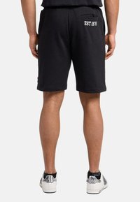 Black cotton shorts with elastic waist, side pockets, and "EST 1978" embroidered in white on the back; flat hem design.