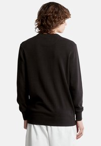 Maglione nero con scollo rotondo, maniche lunghe e polsini e orlo a coste. Texture liscia; vista posteriore che mostra dettagli di cucitura minimi.
