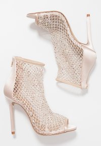 Botines de tacón alto en satén rosa claro con un revestimiento de malla de patrón de diamante, adornados con cuentas de colores y un diseño de punta descubierta.