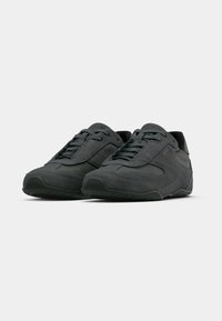 Paire de baskets lacées en daim et cuir gris foncé avec logo de la marque sur les côtés, positionnées en angle vers l'avant sur fond blanc.