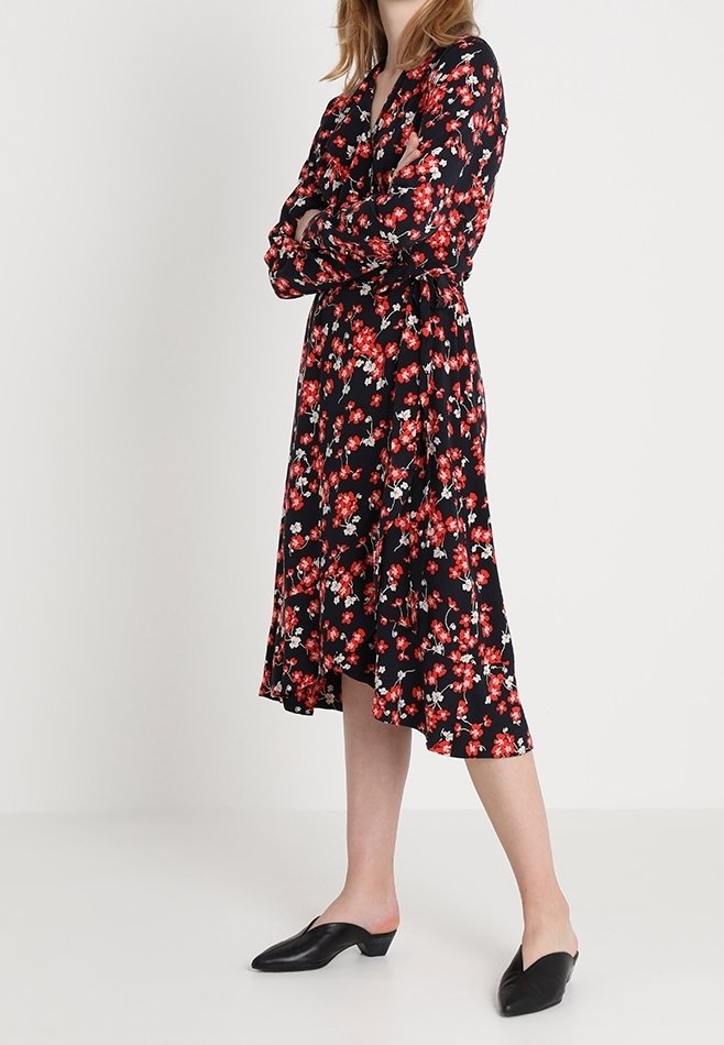 Musta kukallinen mekko punaisilla ja valkoisilla kukilla, pitkät hihat, kietaisumalli, polvipituinen helma, yhdistetty mustiin tasapohjaisiin kenkiin.