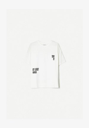 Bijela pamučna majica s kratkim rukavima. Na gornjem desnom dijelu nalazi se crni otisak teksta: "ISPROBAJ" i "BAR JEDNOM" na donjem lijevom dijelu.