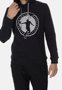 Sudadera negra con un estampado gráfico que presenta a un jugador de baloncesto. Tiene cordones texturizados y puños acanalados. La tela parece suave y elástica.