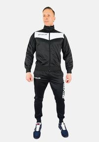 Black athletic tracksuit made of smooth fabric with white accents. Features a zip-up jacket and elastic waistband pants with logo details.