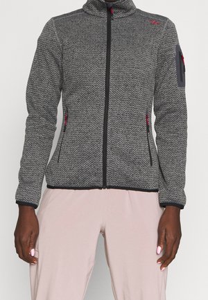 Grå tekstureret fleecejakke med lynlås og sort kant samt lyserøde lynlåstræk, båret med lyserøde bukser.