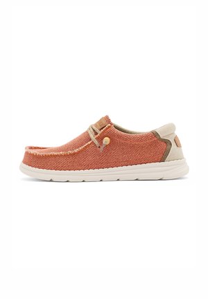 Zapato casual sin cordones con tejido de tela naranja óxido, detalles en beige, suela color blanco roto, detalle de cordones y puntera cosida estilo mocasín.
