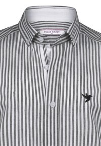 Camisa de botón de rayas para hombre en talla mediana, con rayas verticales en blanco y gris, y un pequeño logo de colibrí negro en el pecho.
