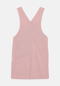 Rosa bomullsoveraller med brede stropper, en bakstykke søm og en sidelomme. Designet har en rett snitt og stikt kanter.
