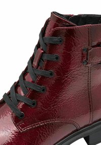 Bottine en cuir verni bordeaux avec des lacets noirs, des œillets en métal et une surface texturée, dotée d'une semelle noire robuste.