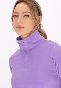 Lilla fleece quarter-zip top med en blød tekstur og høj krave. Har en front lynlåslukning og tætsiddende design.