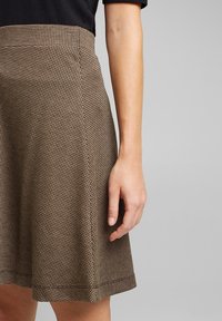 Bruine geruite rok met een uitlopend ontwerp, gemaakt van gestructureerde stof. Heeft een aansluitende taille en een zoom die boven de knie eindigt.